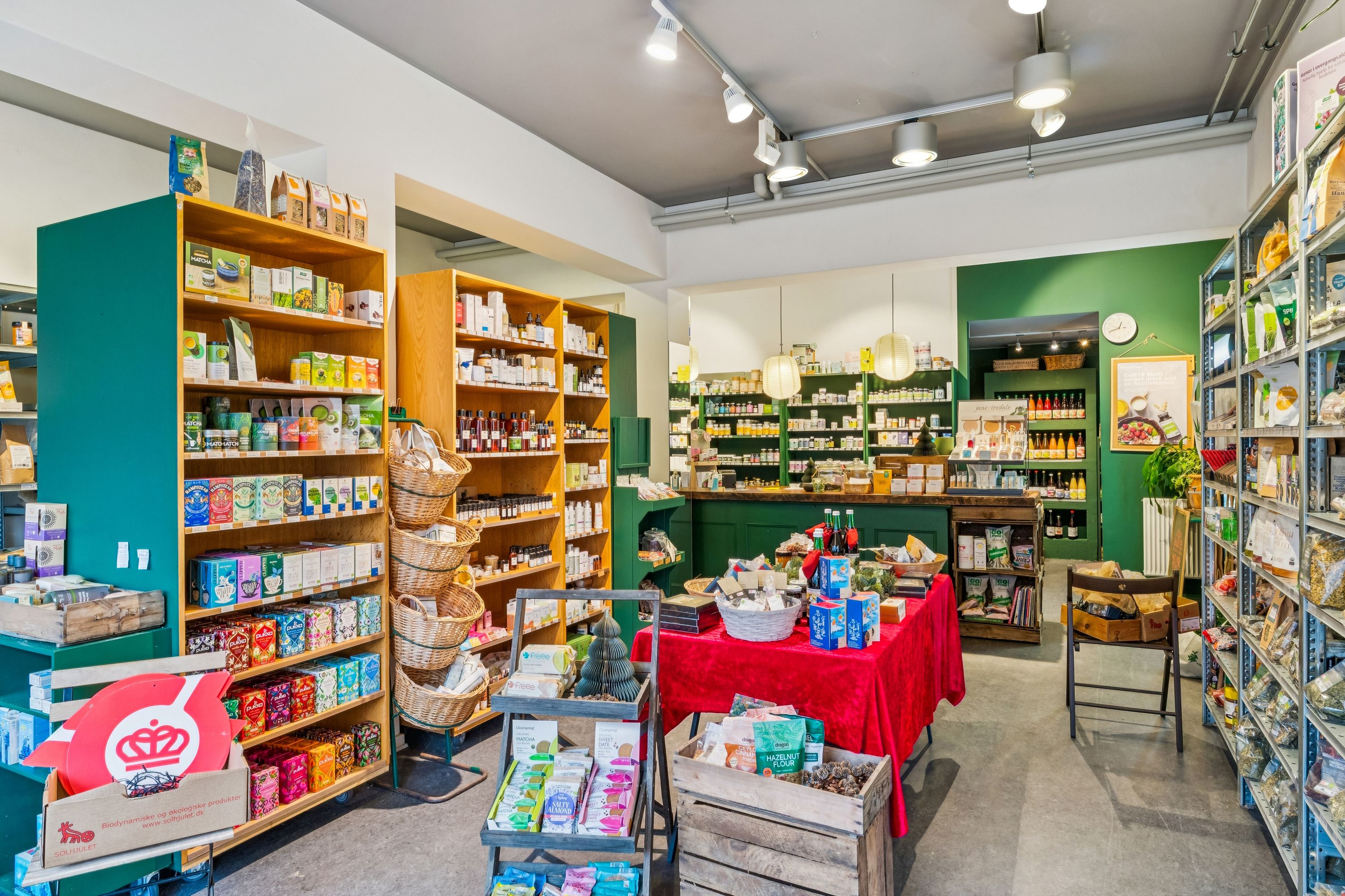 Lys butik med mange hylder og trækurve, lysekroner, røde borde og gulvvedligeholdelse, produkter i alle farver og størrelser, alle sammen tydelige og tydelige.