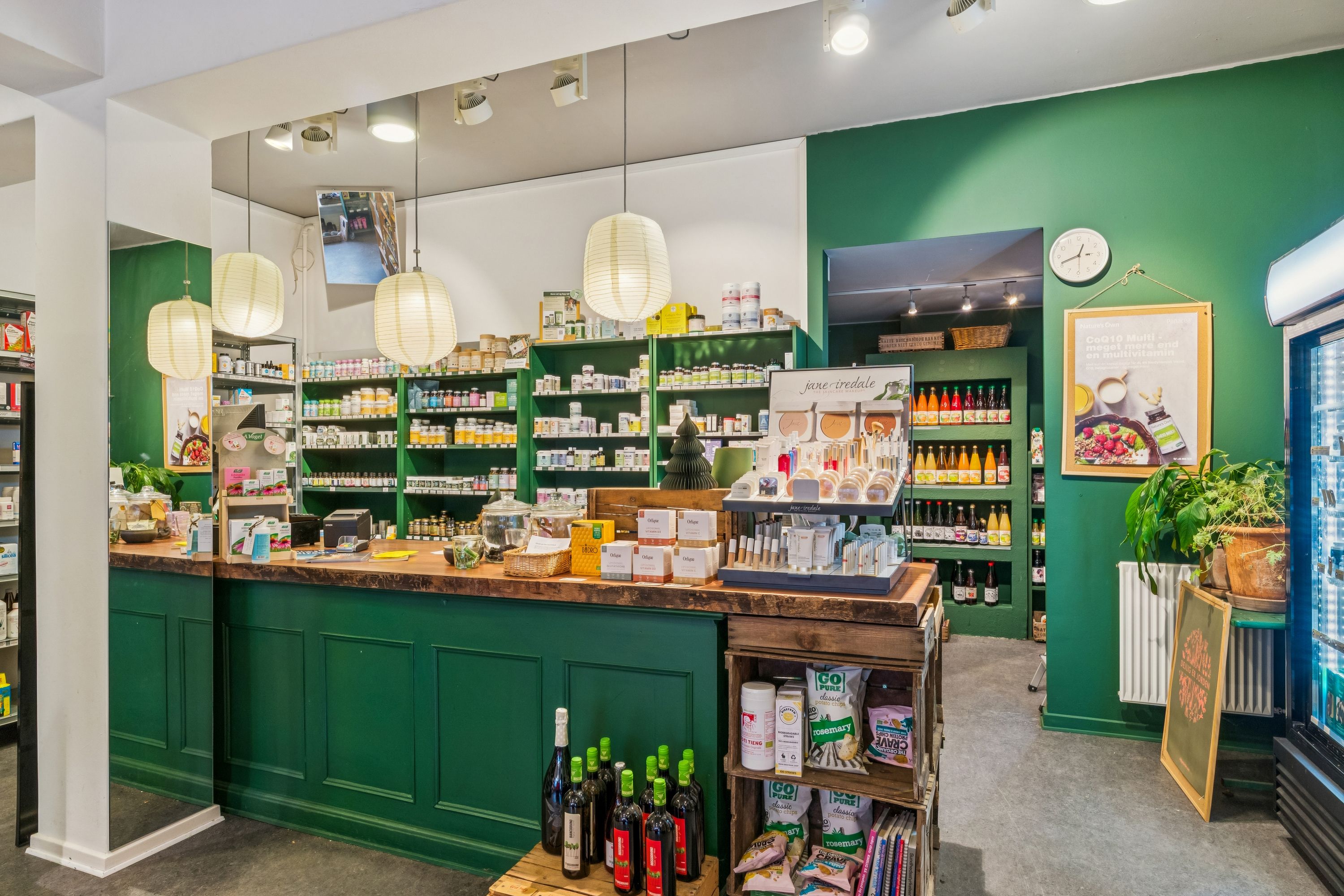 Lyst butikslokale med grønne vægge og hyggelige lanterner. Dekorativt med plantepot, køkkenudstyr og diverse produkter. Enhver interesseret i lokalet kan kontakte ejendomsfirmaet for yderligere oplysninger