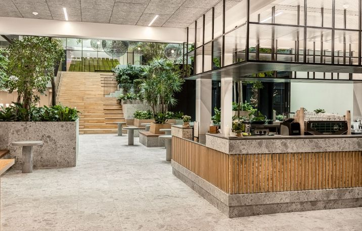 Moderne kontor med højloft, luksuriøs fællesfacilitet, marmor og træelementer, stort plantearrangement og glasvinduer