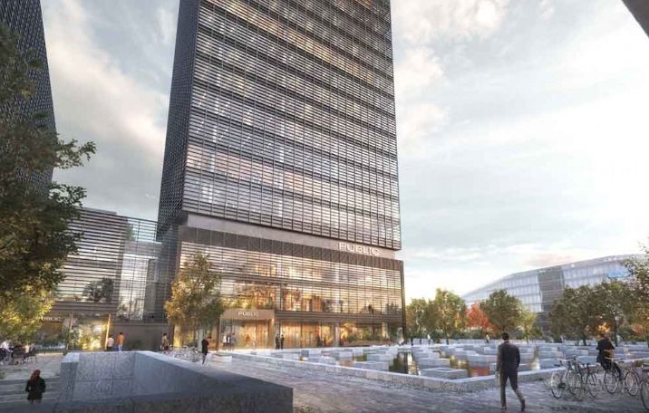 På Kay Fiskers Plads 11 i København S er der en stor kontorbygning med luksuriøse fællesfaciliteter. Mennesker går rundt i forgrunden med en bygning i baggrunden, og der er træer og en vandfontæne