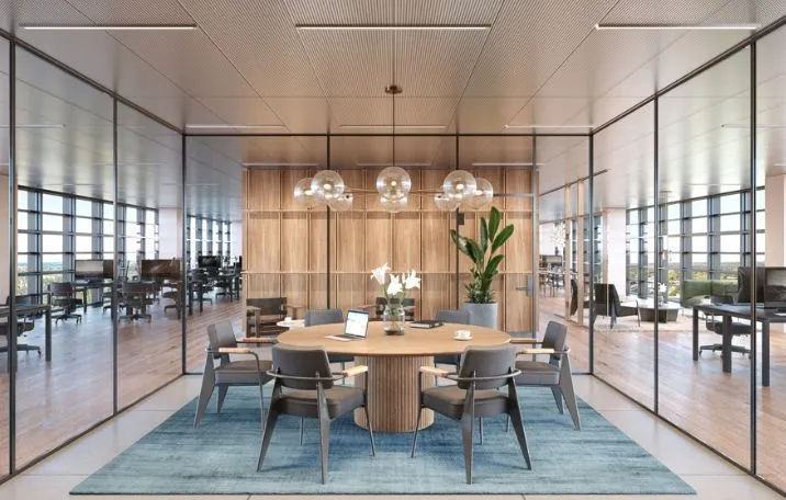 Kontor med mødelokaler, hvide loftspaneler og lyse loftslamper. Et stort træbord med computere og mødestoler samt en plante i en krukke.