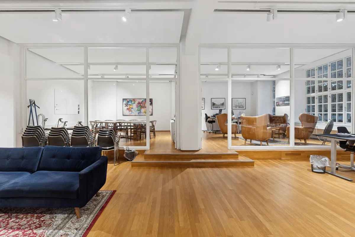 Lyst og moderne kontorrum med trægulv og møbler, fuld længde spejl og stolpe, lyse loftslys, terrasse og spisestue med borde og stole