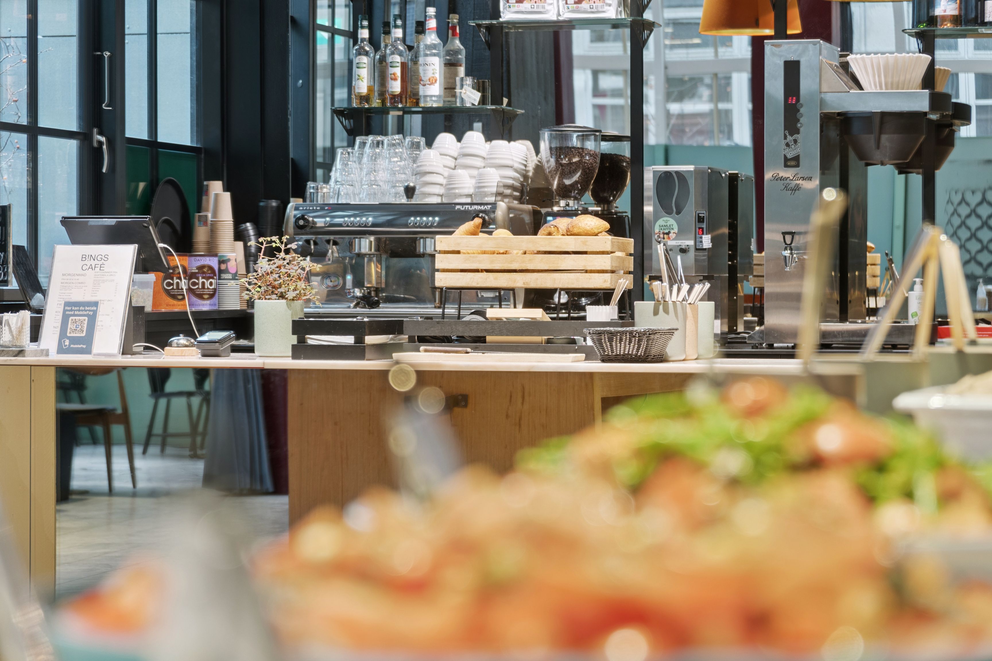 Lyst og moderne kontor i København med høj loftshøjde og privat terrasse. Kaffemaskine, friske croissanter, grøntsager og snacks. En afslappet atmosfære til ro og produktivitet.