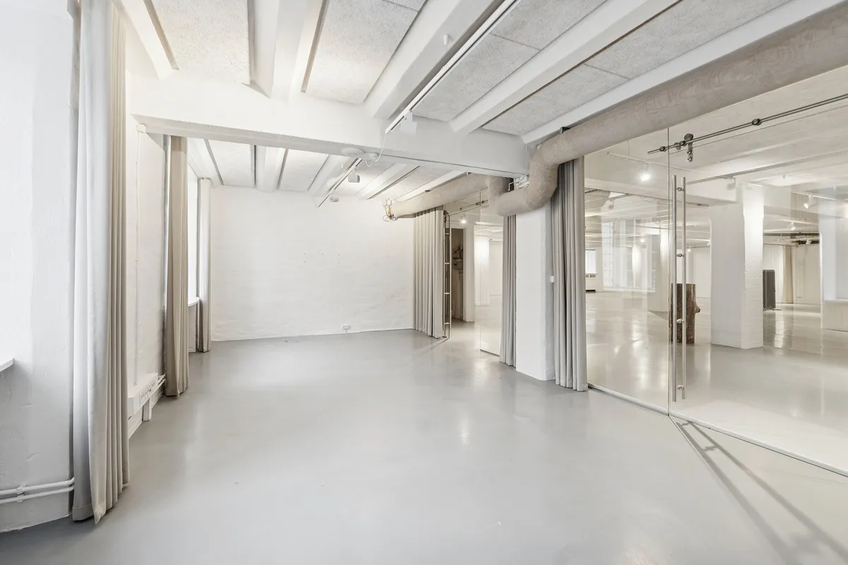 Væggene og gulvet er malet hvidt, der er store glasruder og store gardiner i det ene hjørne