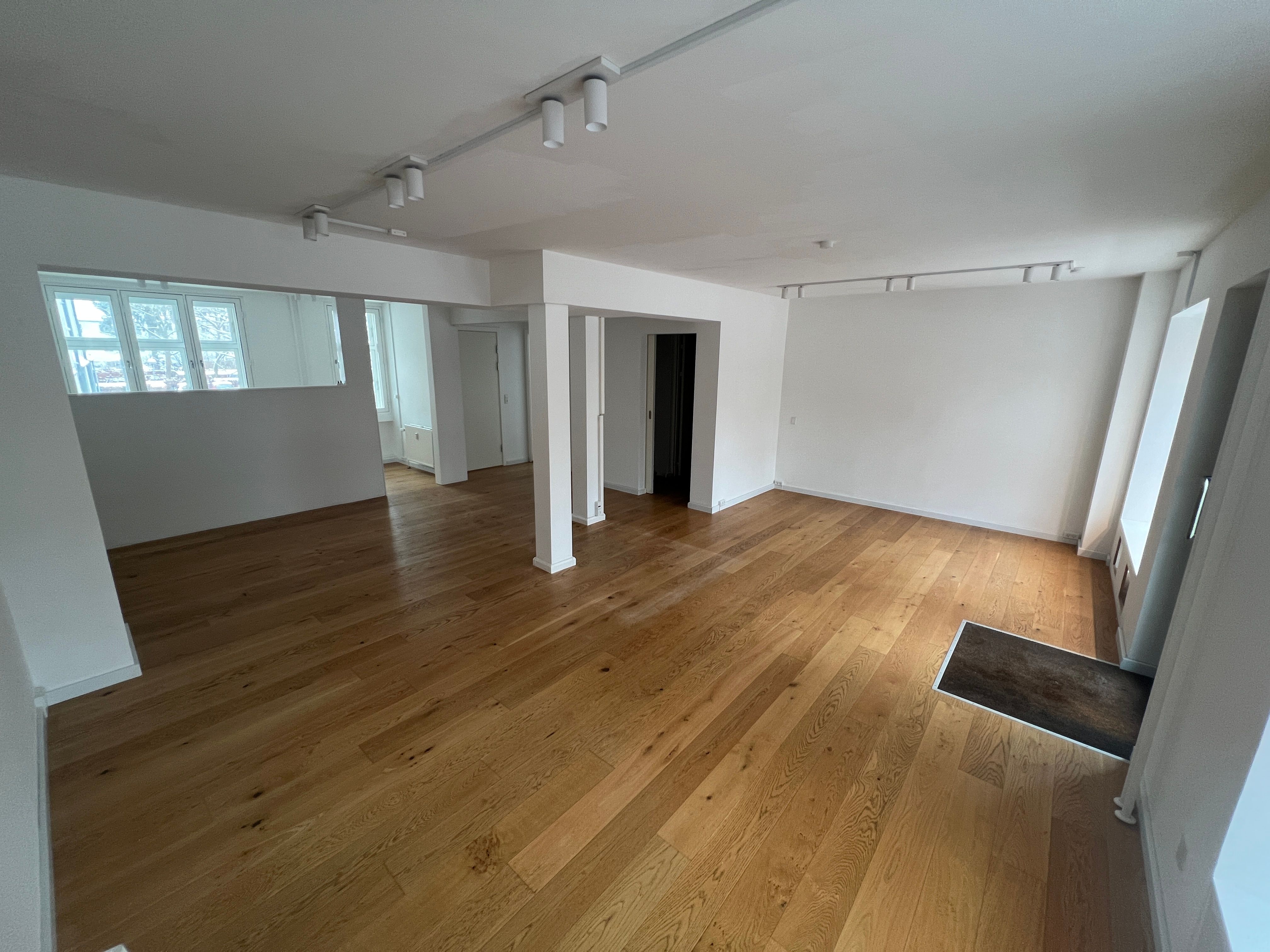 Store, lyse og indbydende lokaler med lysegule trægulve og hvide vægge til leje i Kongens Lyngby. Lokalerne har højloft og vinduer til alle sider