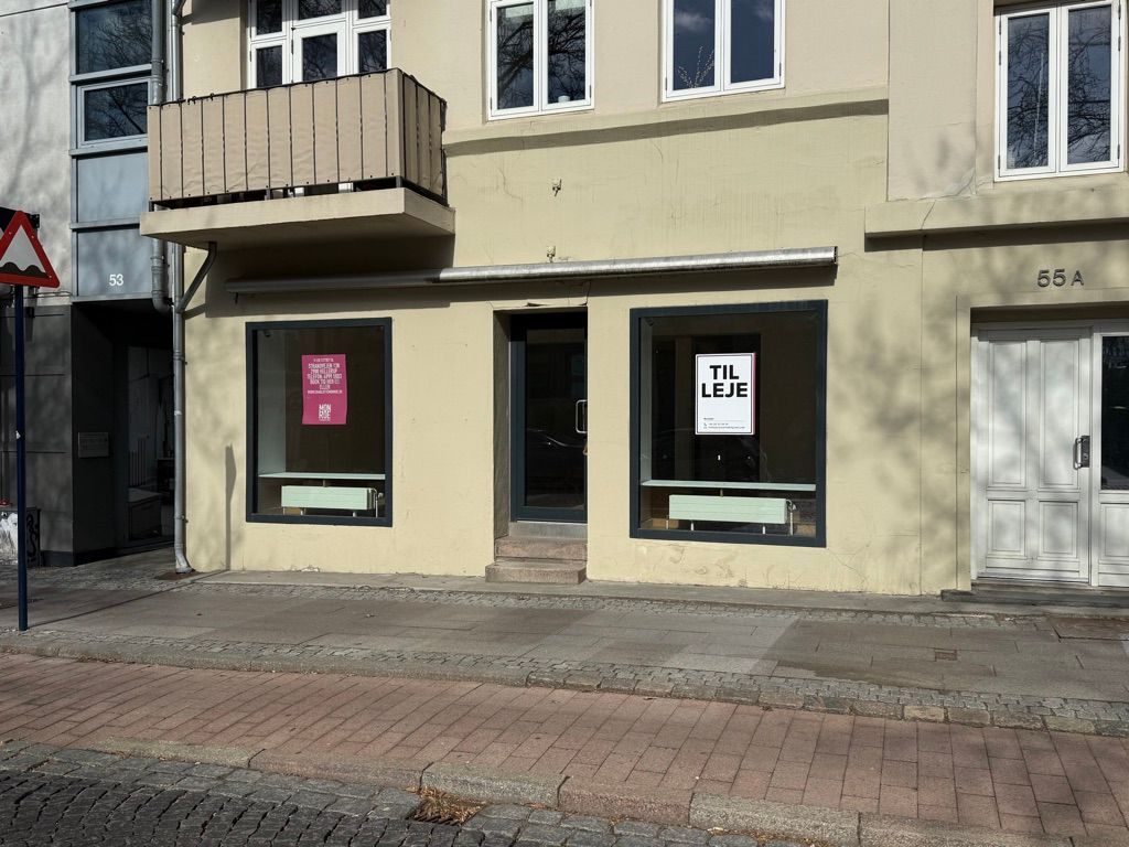 Byggegrund til leje i Kongens Lyngby. Lokal med to store vinduer og møbler i lyse farver. Nummer 55A.