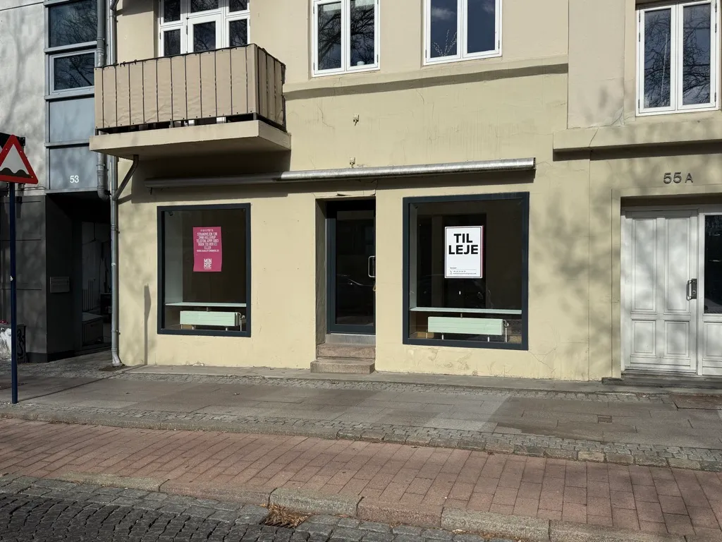 Byggegrund til leje i Kongens Lyngby. Lokal med to store vinduer og møbler i lyse farver. Nummer 55A.