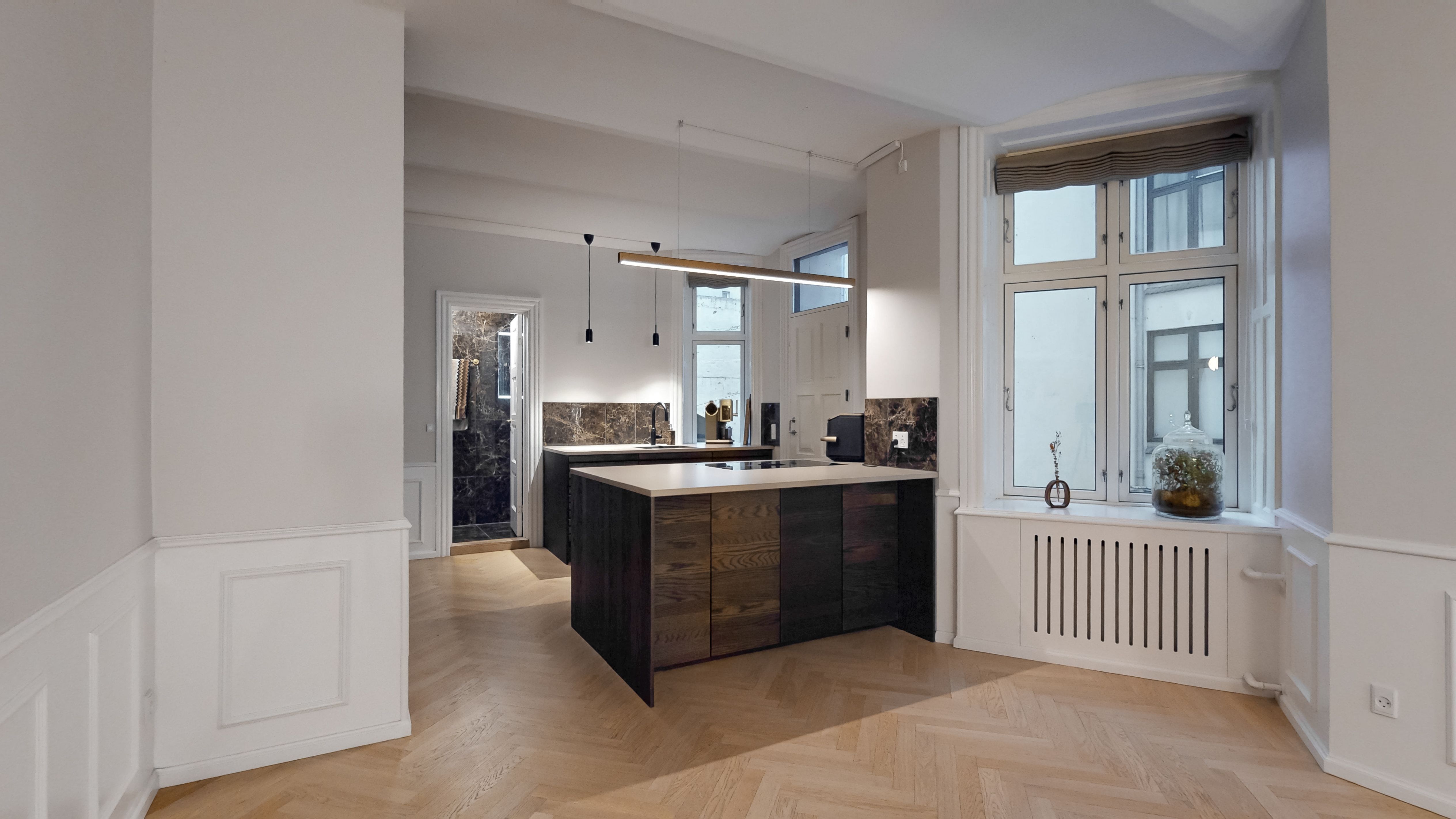 En velbeliggende erhvervsandel med moderne køkken, marmorgulv og lysevinduer på Amaliegade 36. Et minimalistisk design med lysegule vægge og massivt træ