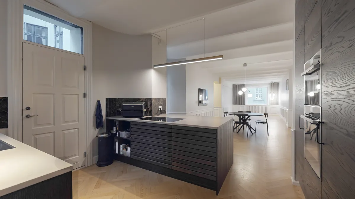 Moderne køkken med øer og luksuskøkkenudstyr i hjertet af København. Sorte møbler og hvide vægge skaber en elegant og minimalistisk atmosfære