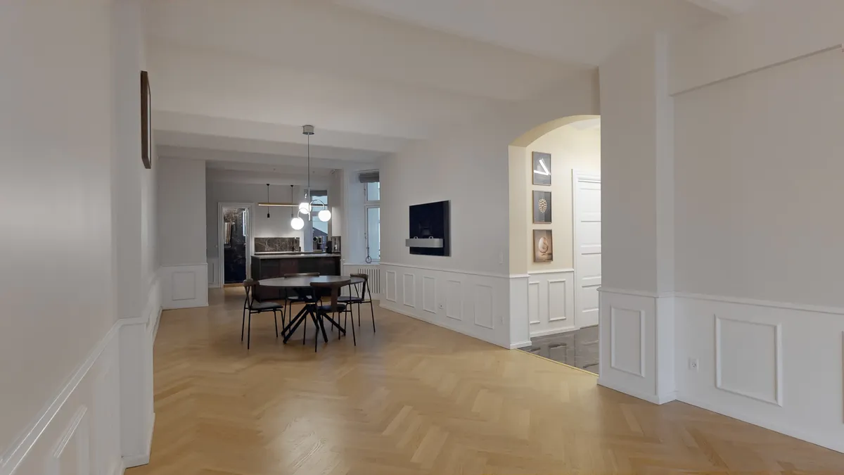 Indvendigt lyst og ryddeligt erhvervslokal med højt til loftet, lyse gulve og hvide vægge samt moderne møbler og teknologi