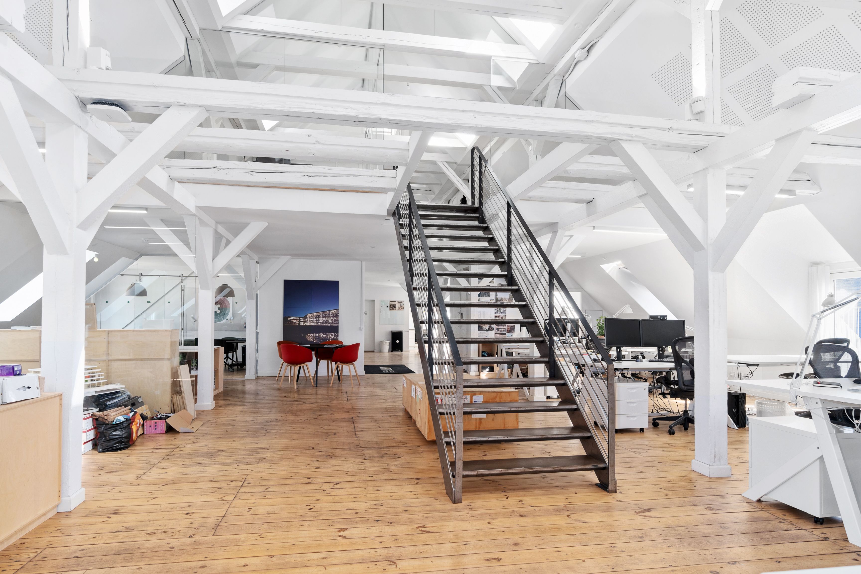 Kontorlokaler med højloft og lyse loftsbjælker, indrettet med højteknologiske skriveborde og moderne kontormøbler i hjertet af Islands Brygge