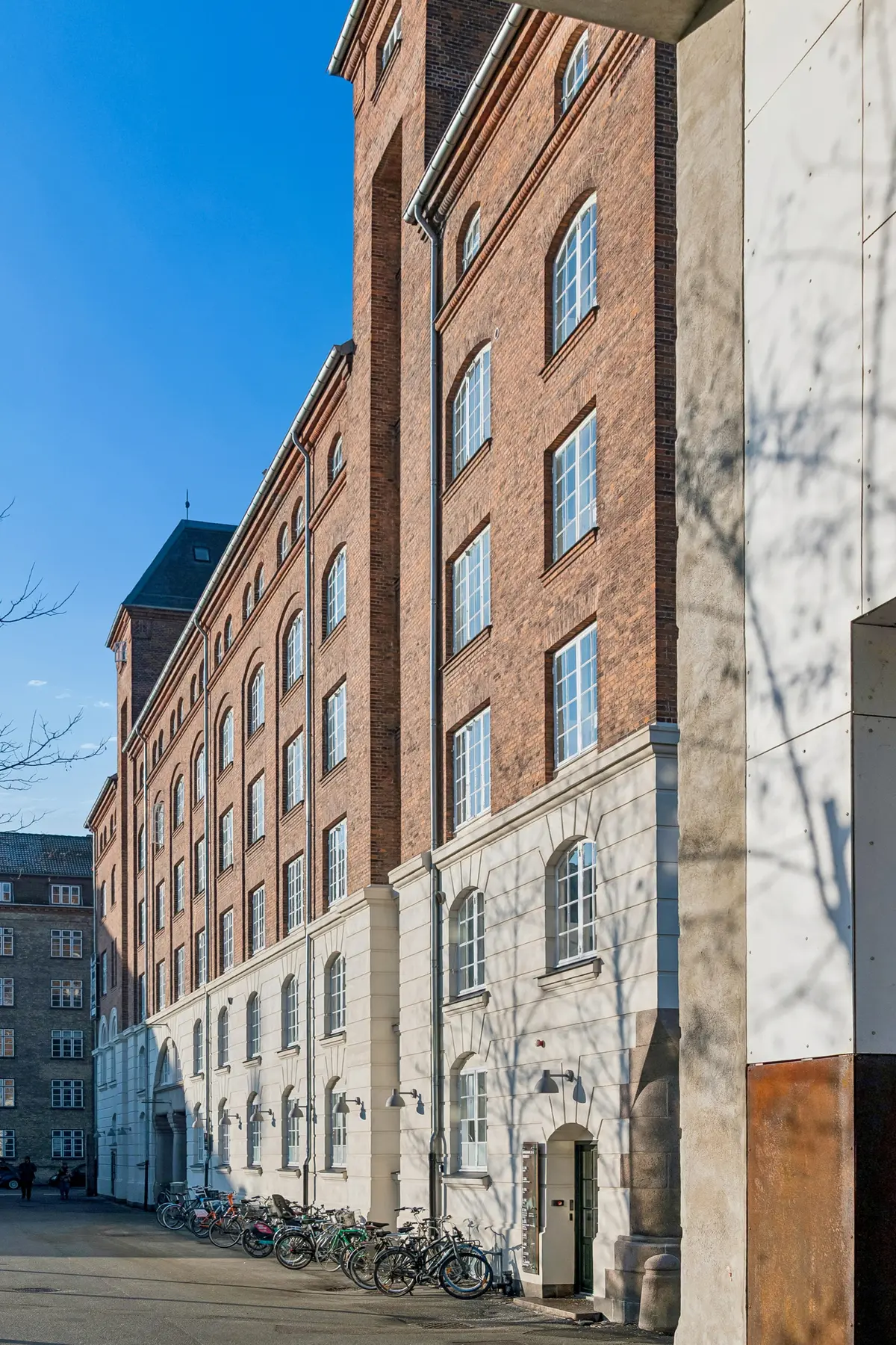 Rå og charmerende erhvervslejemål med industriel stil i Njalsgade 21F, 4., 2300 København S. Stående cykler og brede vinduer i røde og hvide mursten