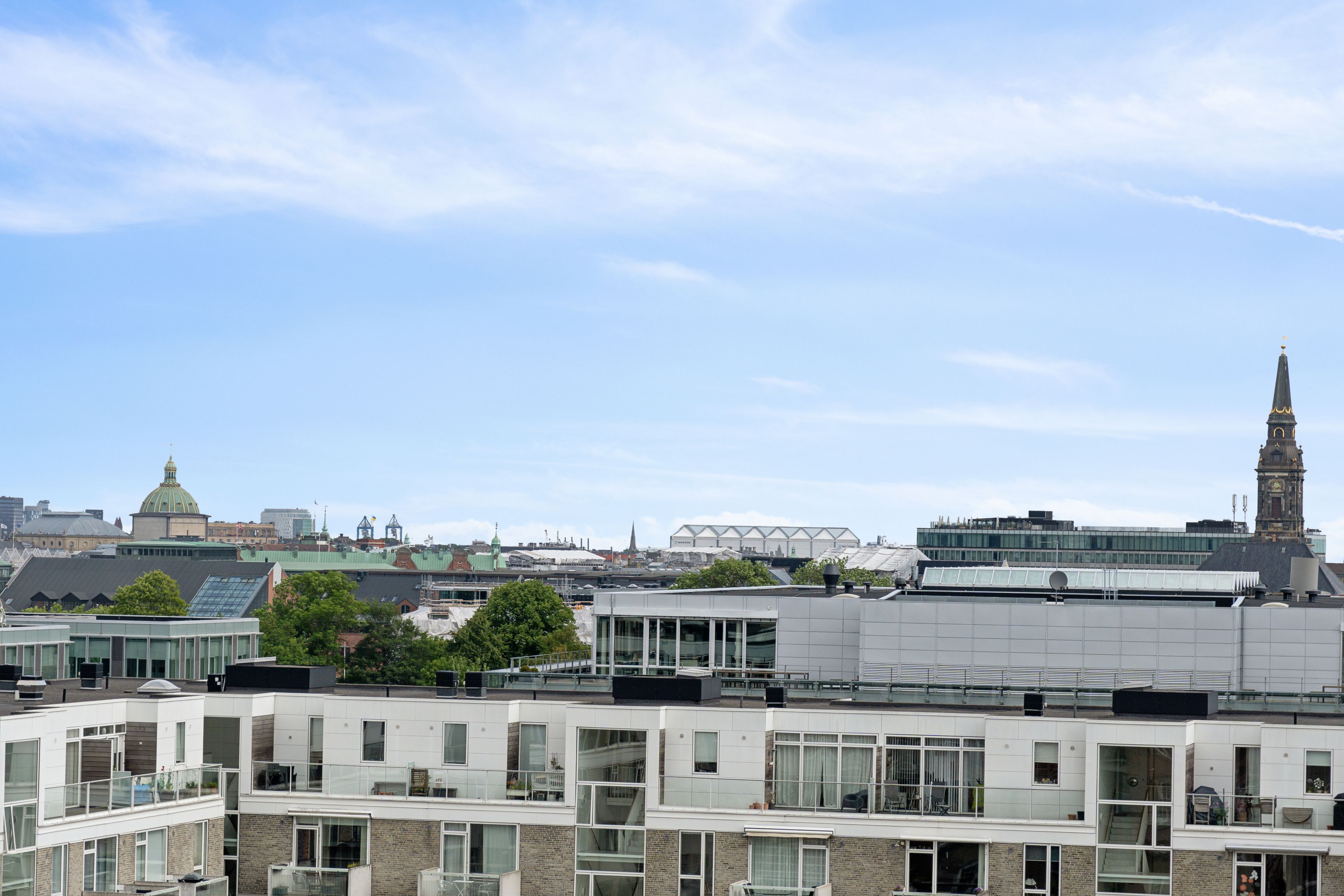 Rå og charmerende kontorlejemål med udsigt over Njalsgade-kvarterets bygninger, glasruder og spiret fra St. Knuds Kirke i baggrunden. Forskellige bygninger og træer.