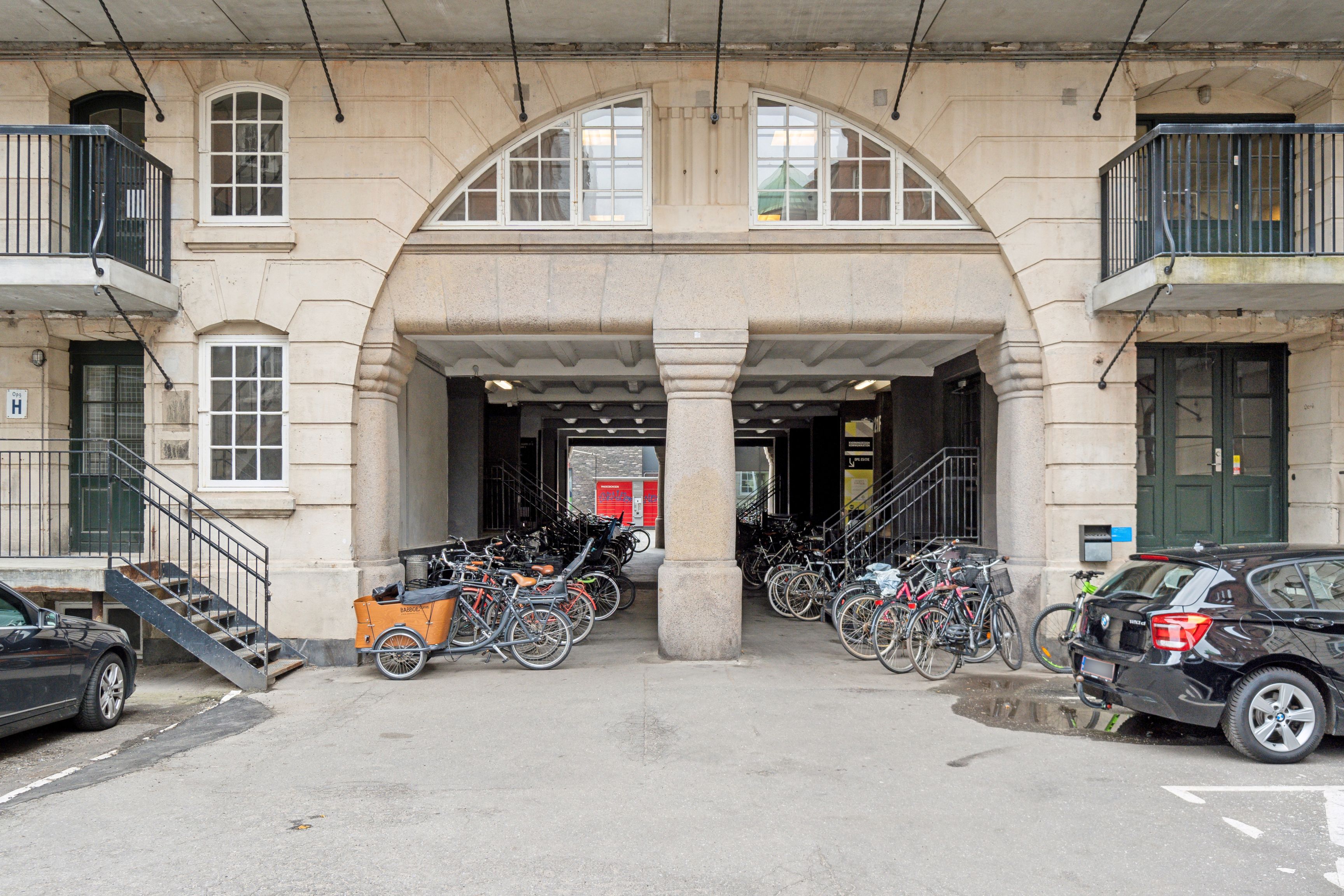 Kontor i Njalsgade med råt og charmerende erhvervsmiljø. Både biler og cykler parkeret. Vinduesgafler og kolonner. Balkoner med udsigt over gade.