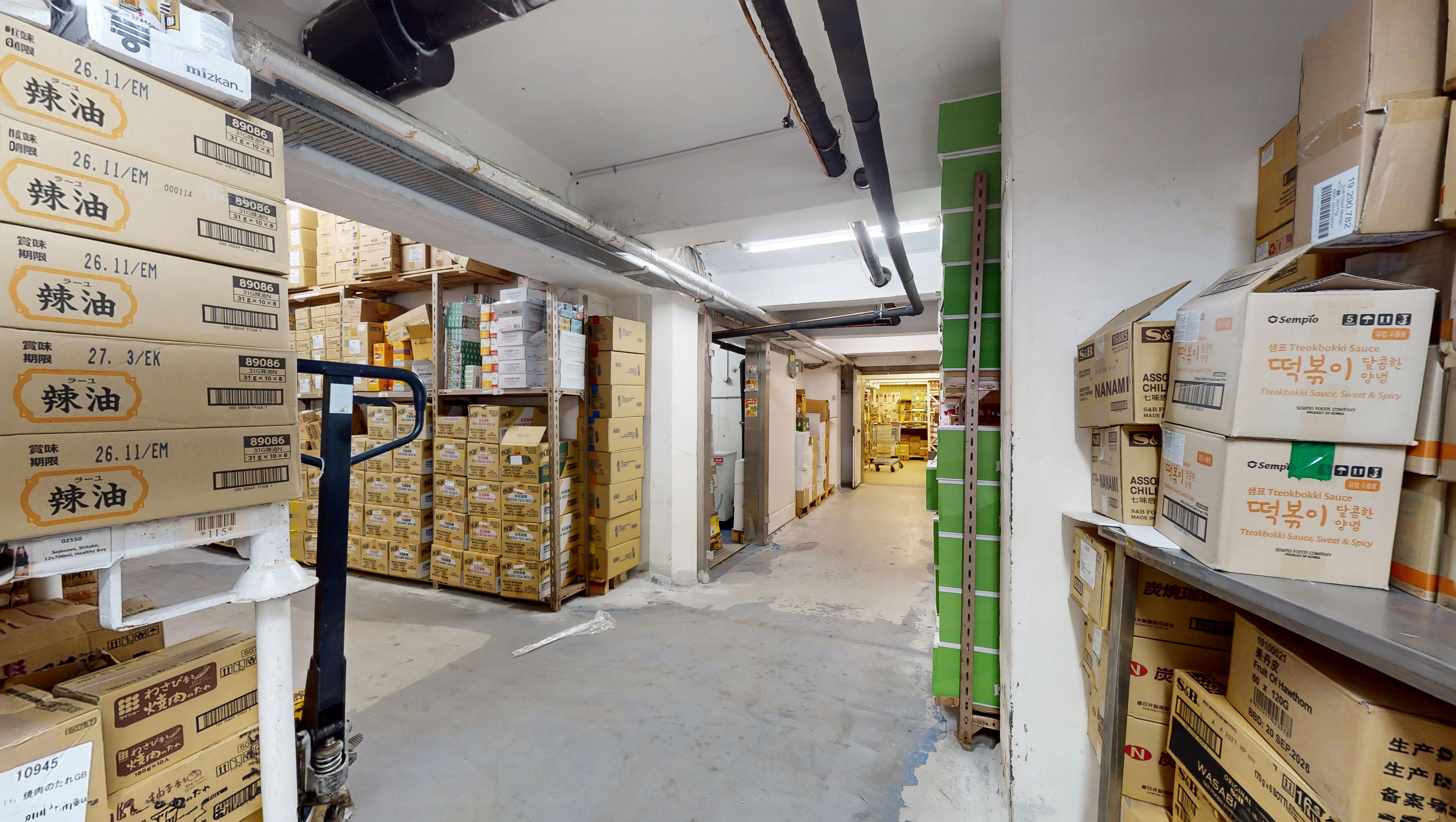Lager med bøsser fyldt med kasser med koreansk mad, lagerreol, gulve og lofter, ventiler og røgrøg.