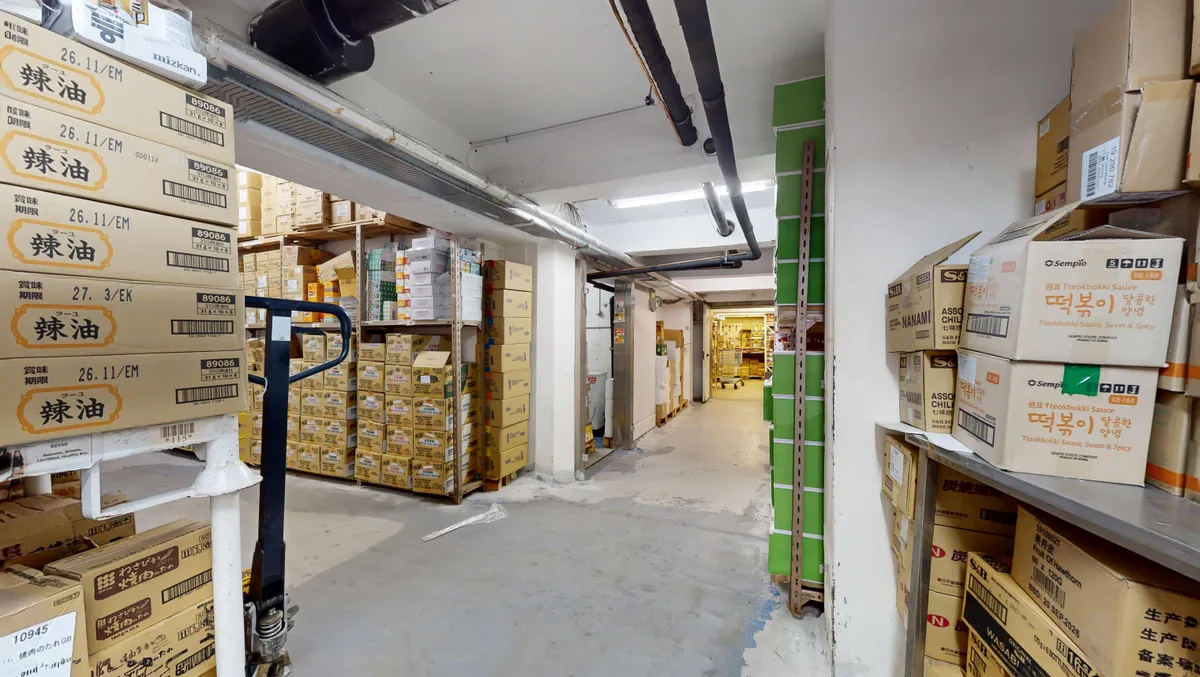 Lager med bøsser fyldt med kasser med koreansk mad, lagerreol, gulve og lofter, ventiler og røgrøg.