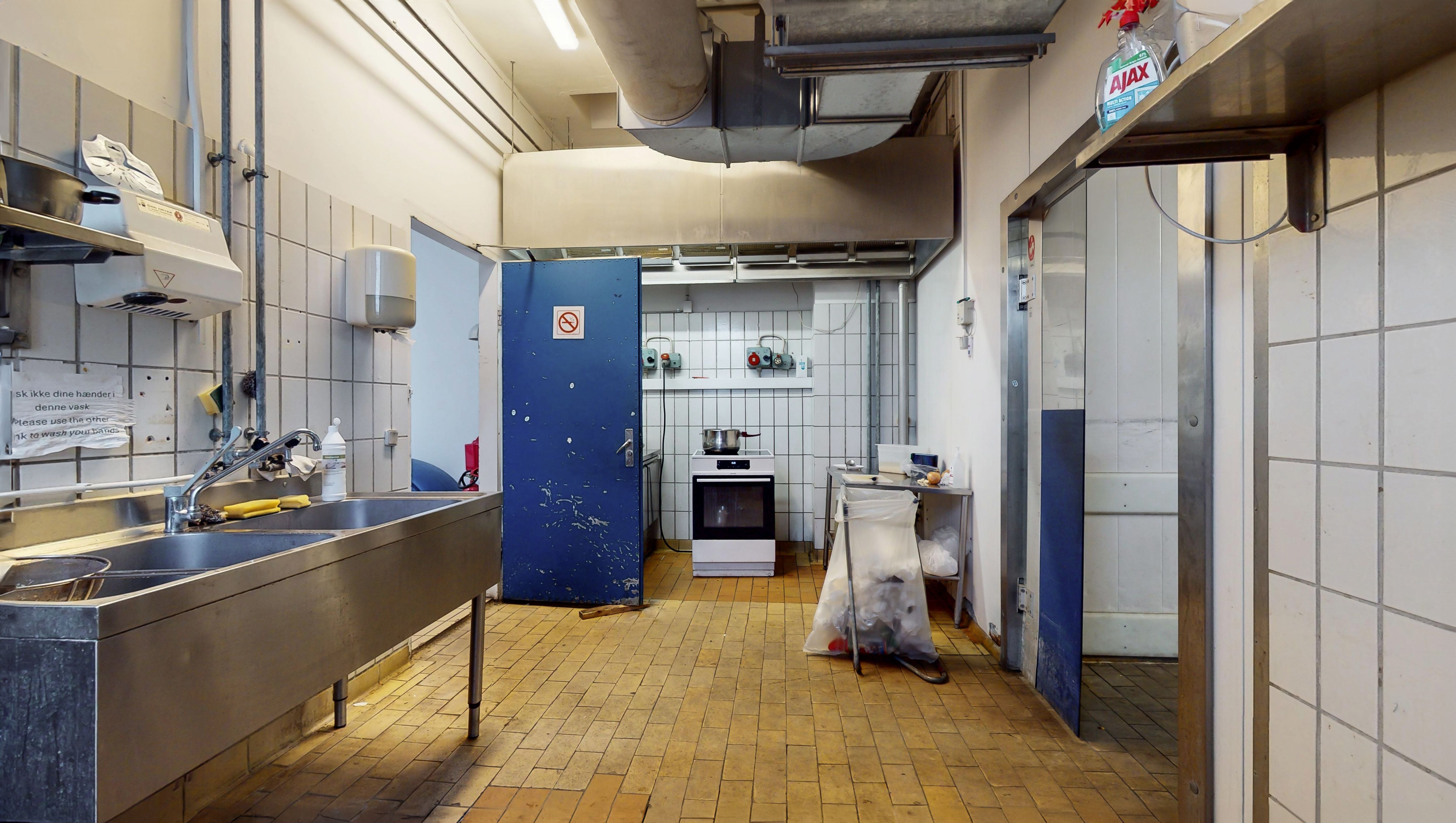 Funktionelt erhvervslejemål med dobbelt vask og ovn samt opbevaringsmuligheder på gulvet og væggen