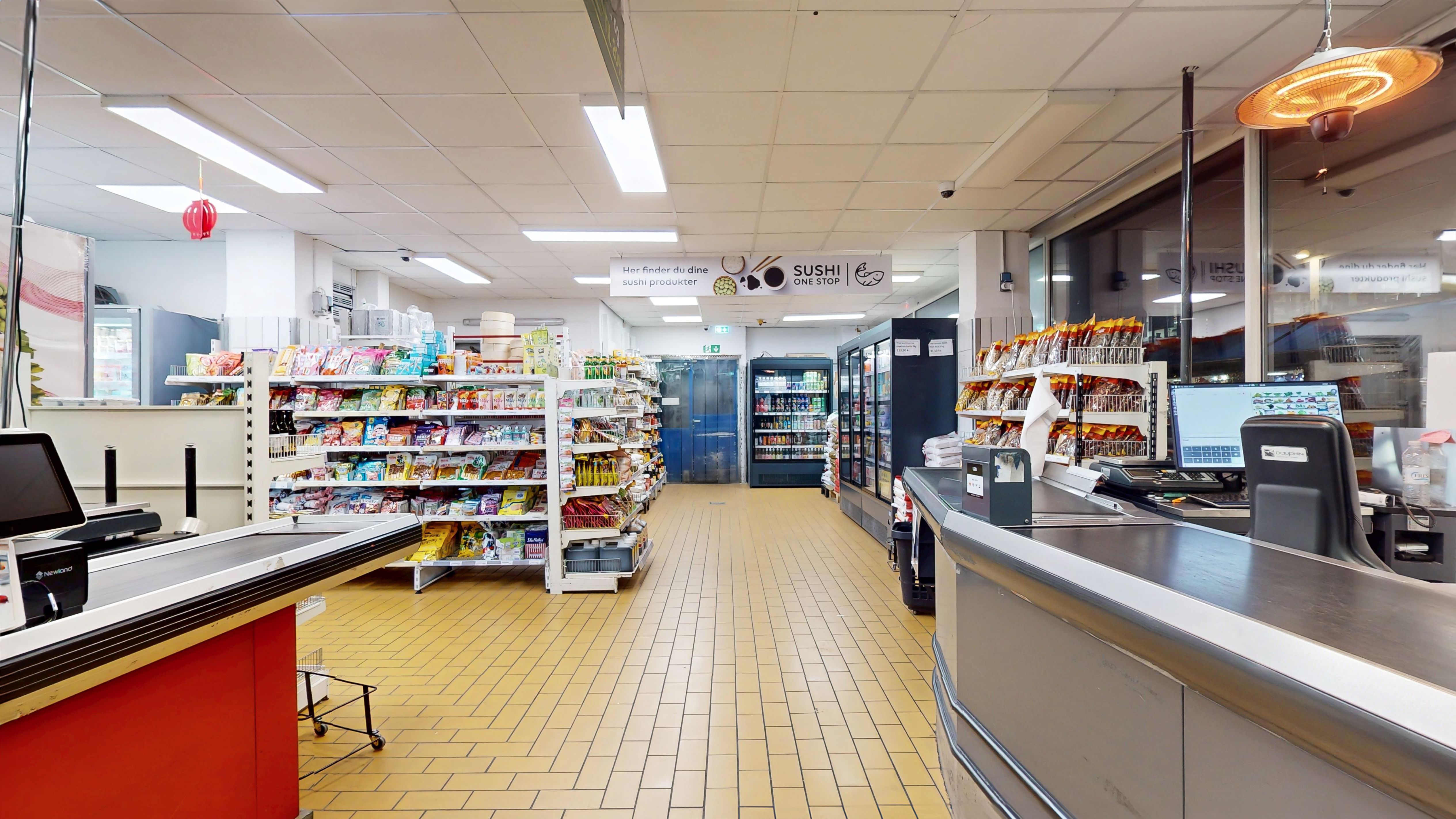 Forretningslokaler med salgsstander, køleskabe og kasseapparater, salgsregnskabsprogrammer, snacks og varer, gul gulv og hvide loftslys, reklameskilt og videoovervågning