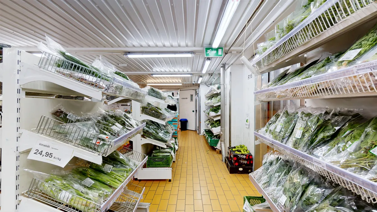 Stort og funktionelt kølelager med mange krydderurter og grøntsager i plastikposer, priser og udvalg på hylderne