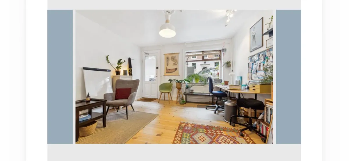 Et moderne og rummeligt kontor med lyse lofter og vinduer. Bord med stol og skrivebord samt en stol og skrivebord med flere bøger og plante