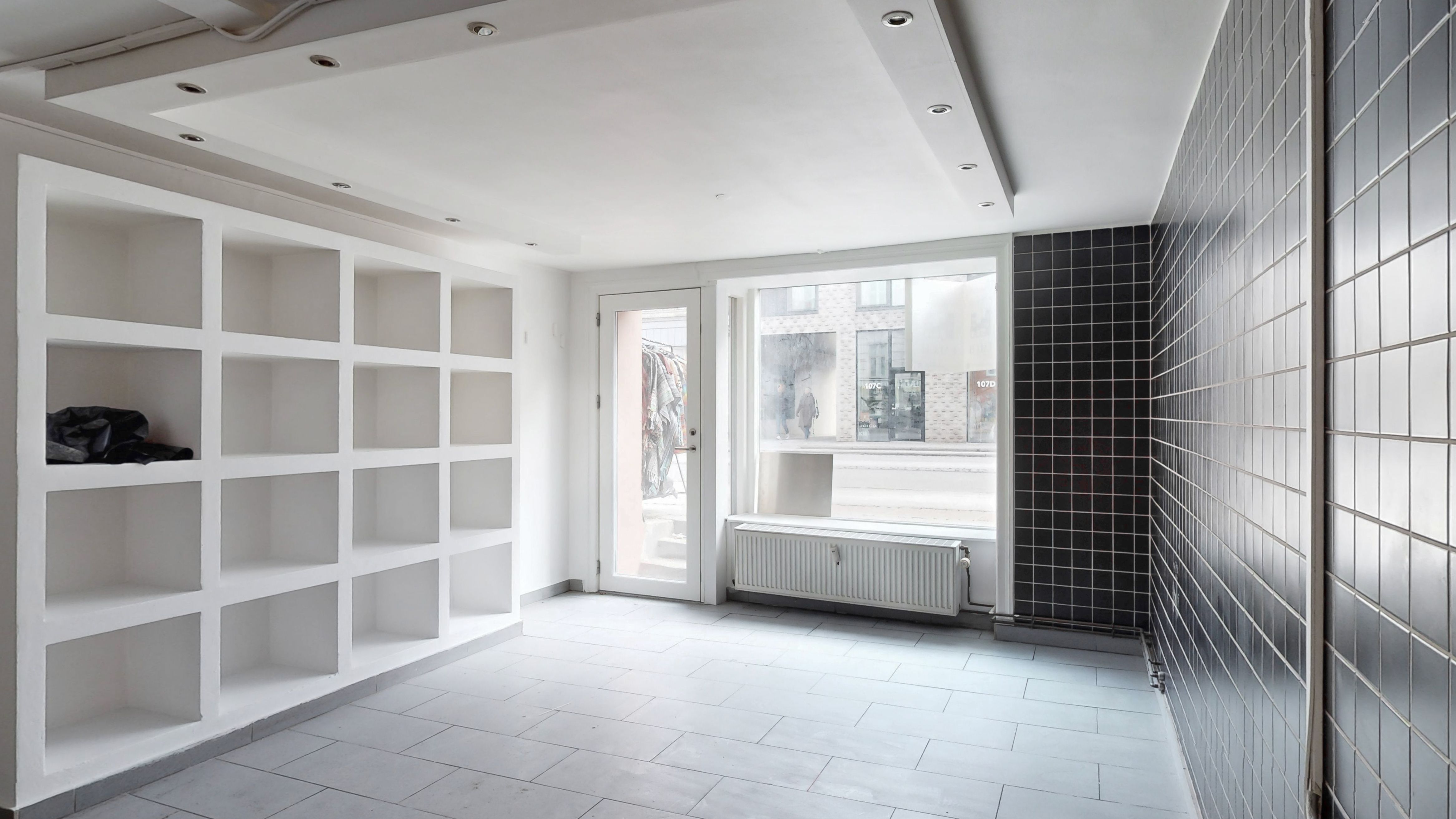 Et nyt, rent og velrenoveret erhvervslejemål med højloft, lyse og lyseglasvinduer, nye radiatorer, hvide hylder og moderne gulvbelægning samt et nyt køkken