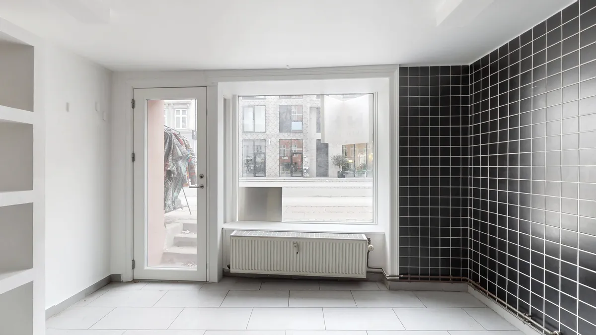 København V, erhvervslejemål, 51 m², hvidt interiør, gulv, radiator, sort og hvidt tøj, udsigt til Vesterbrogade, bygning, solskinsrefleks