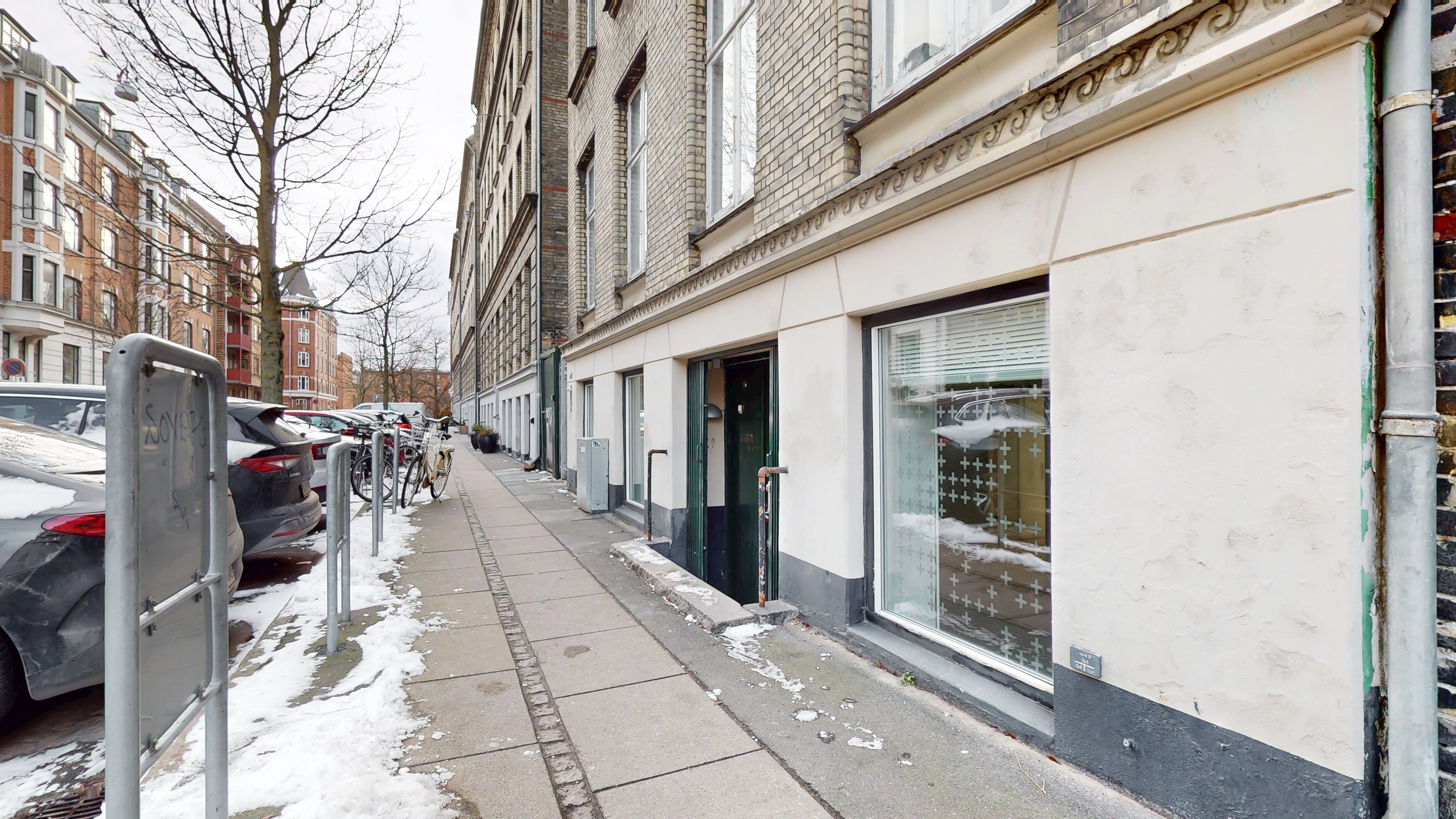 Erhvervslejlighed med udsigt til gårdhave og parkerede biler på siden af gaden