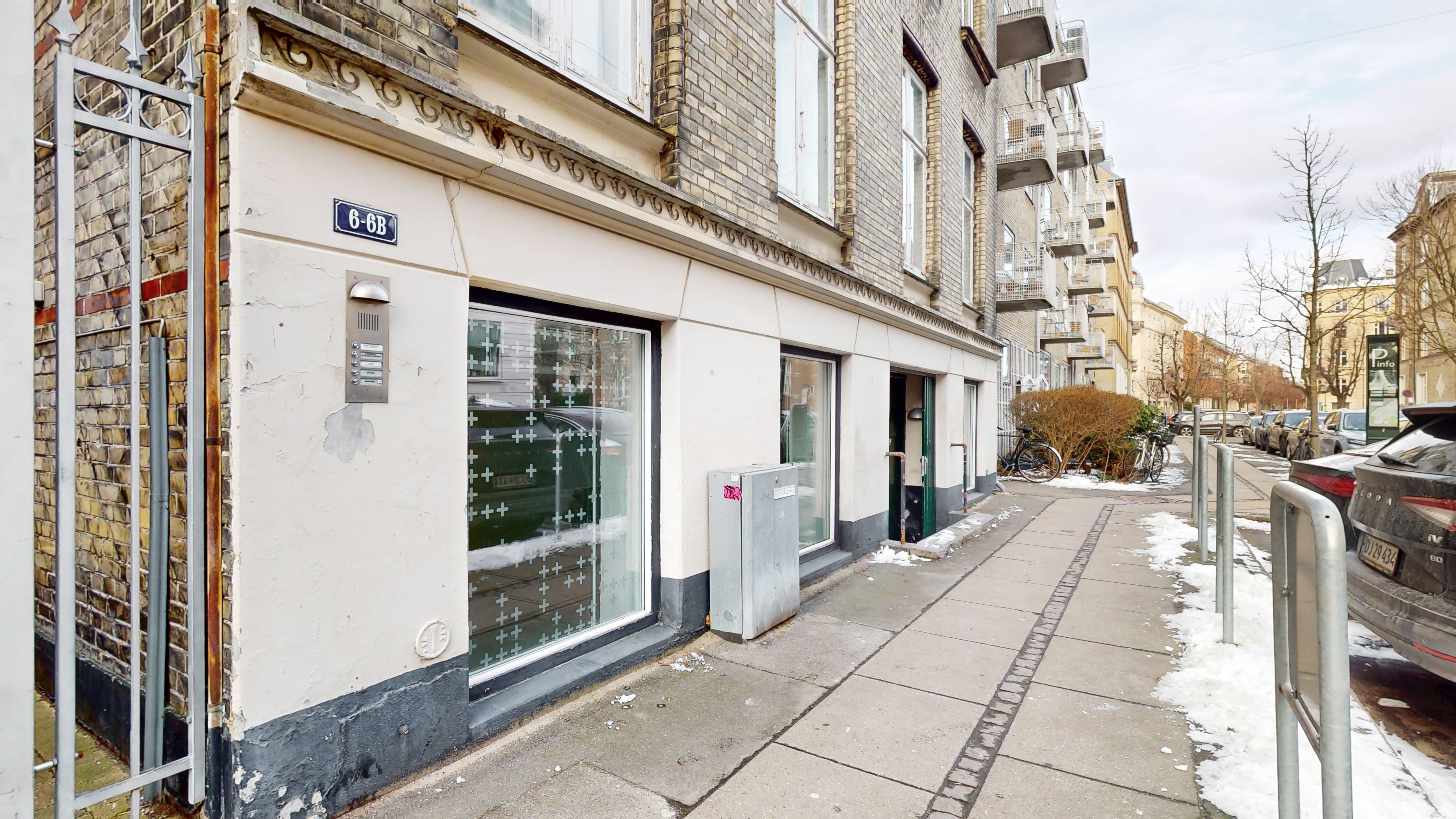 En hyggelig sidegade med en erhvervsejlejlighed og et parkerede biler og en snedækket fortov