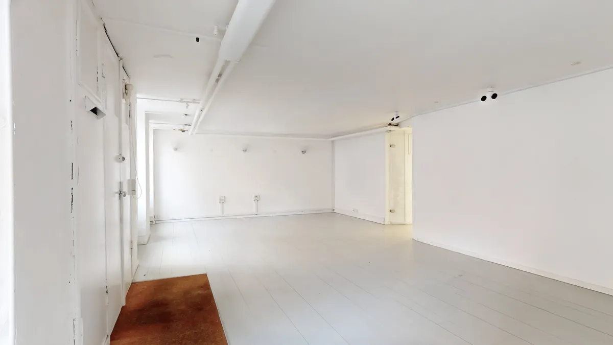 Tomme og hvide lokaler med hvidgulv og hvide vægge, hvor der er åbninger til to værelser