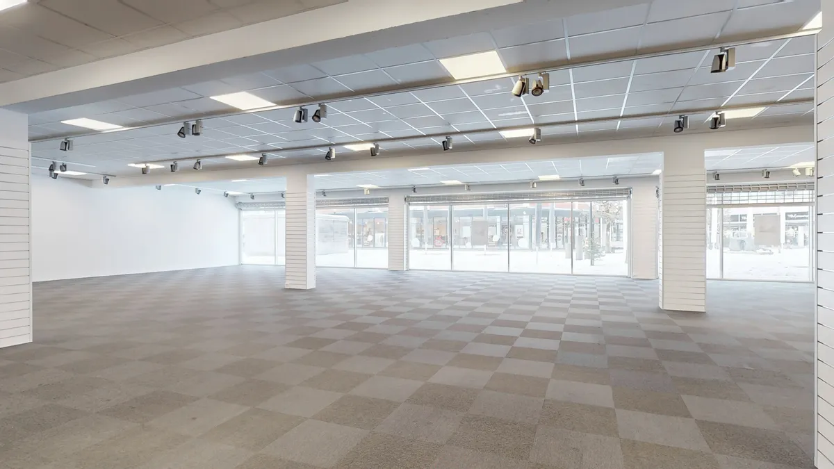 Et velbeliggende erhvervslejemål med hvide vægge, krydsformede loftslys og krydsformede gulvfliser i Birkerød