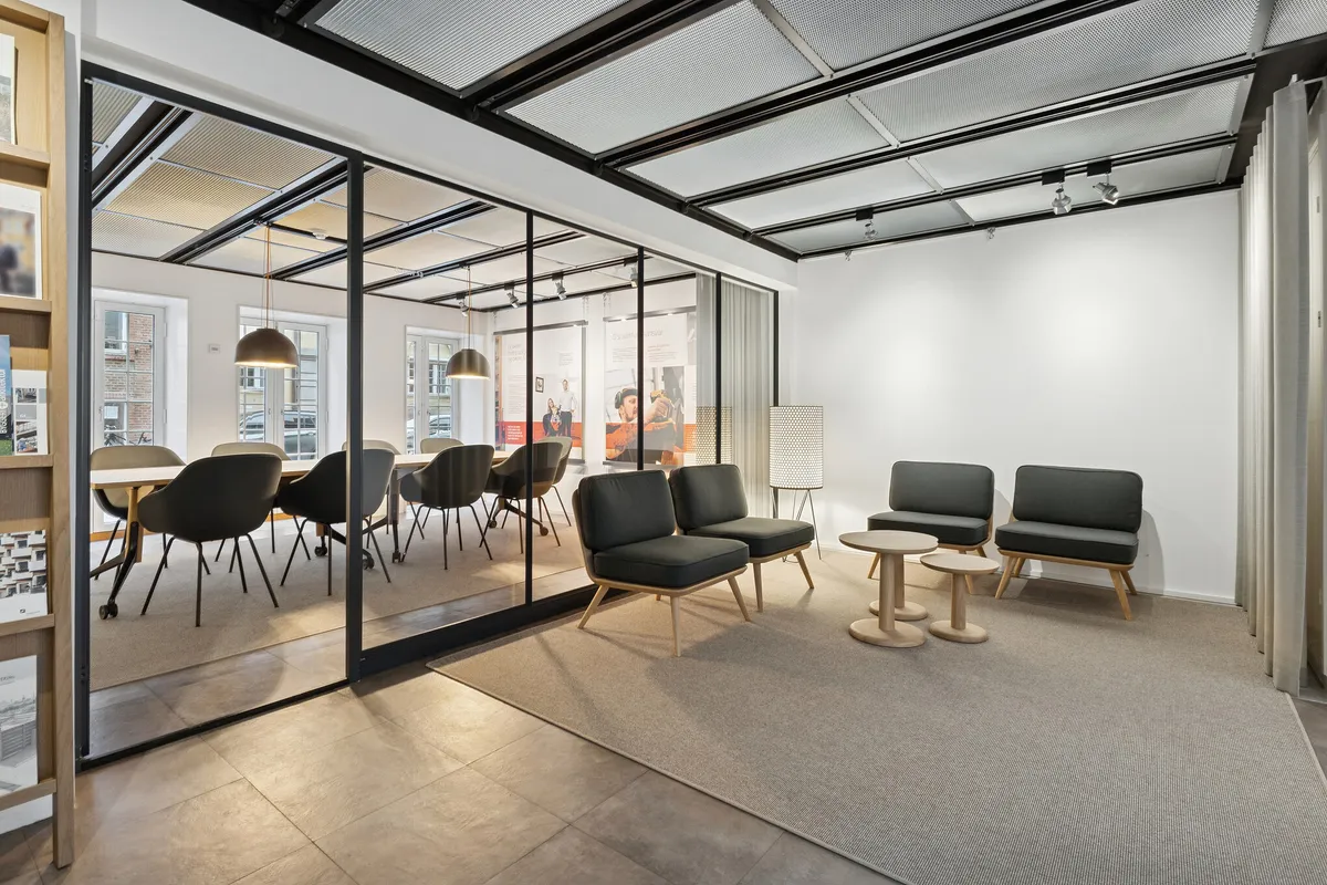 Kontorområde med moderne møbler og store vinduer i lyse farver og lysekroner og moderne lofter i en nyrenoveret bygning i historisk kvarter