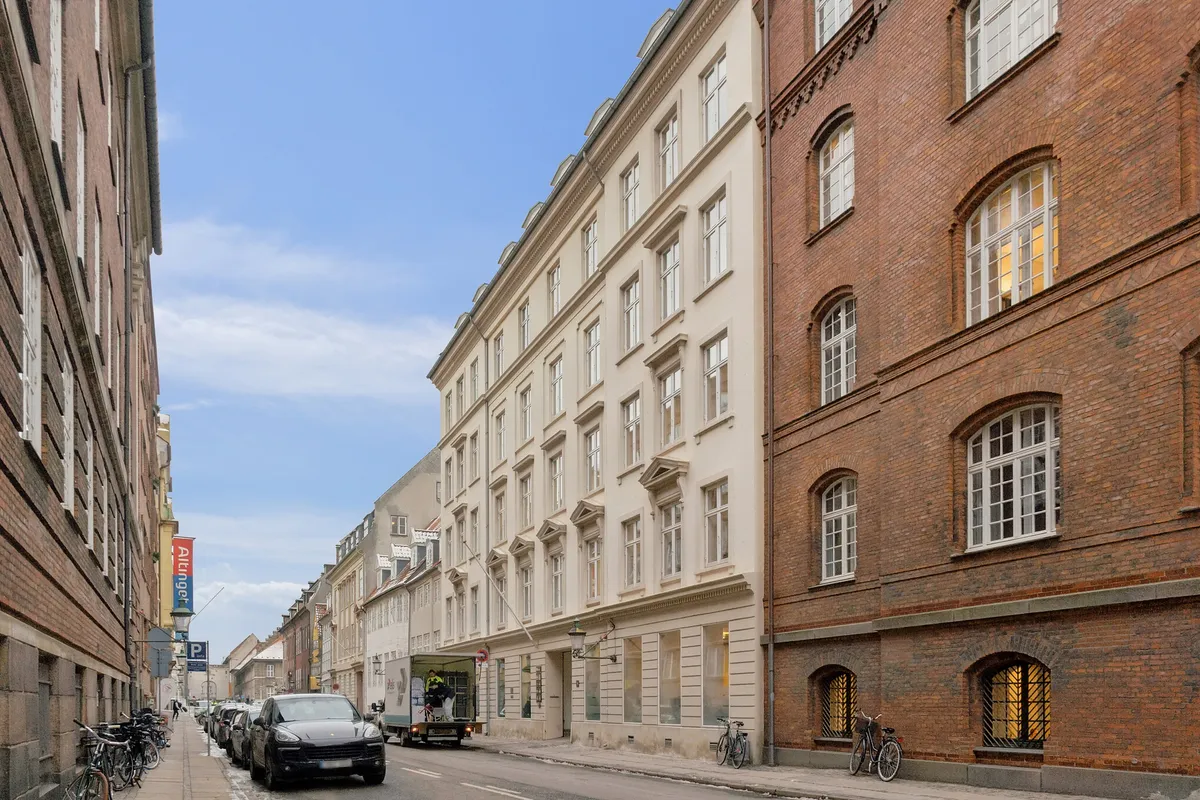 Kontorlejemål i flerbrugerhus med moderne arkitektur og parkerede biler på gågade i Københavns historiske kvarter
