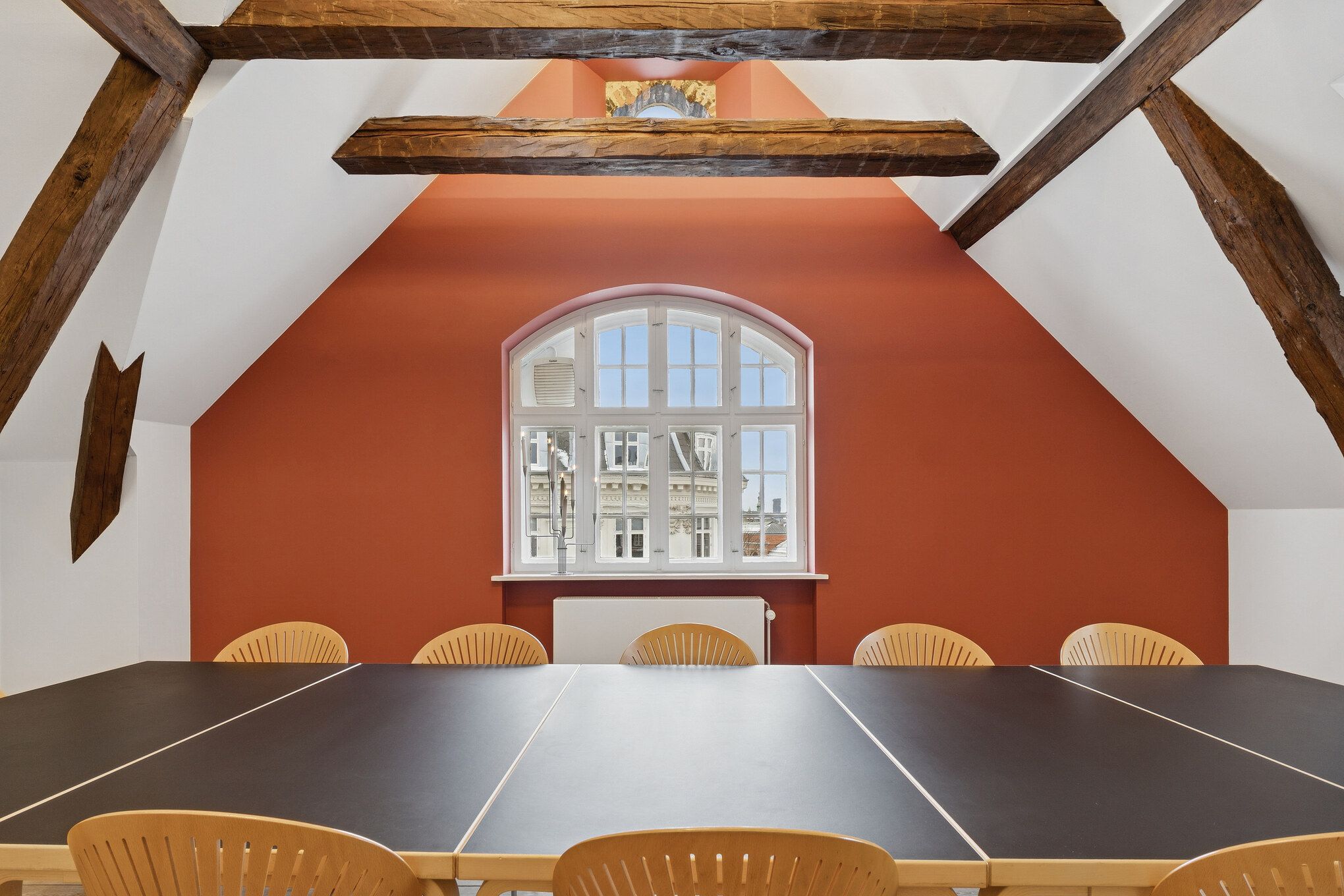 Kontorlokaler med lyse trælofter og røde vægge, slanke vinduer og lyse møbler samt bord og stole i et fredeligt miljø