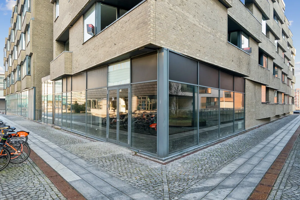 Synlig og indbydende butik til leje på Amerika Plads 34, 2100 København Ø, med store glasruder og parkerede cykler på forsiden