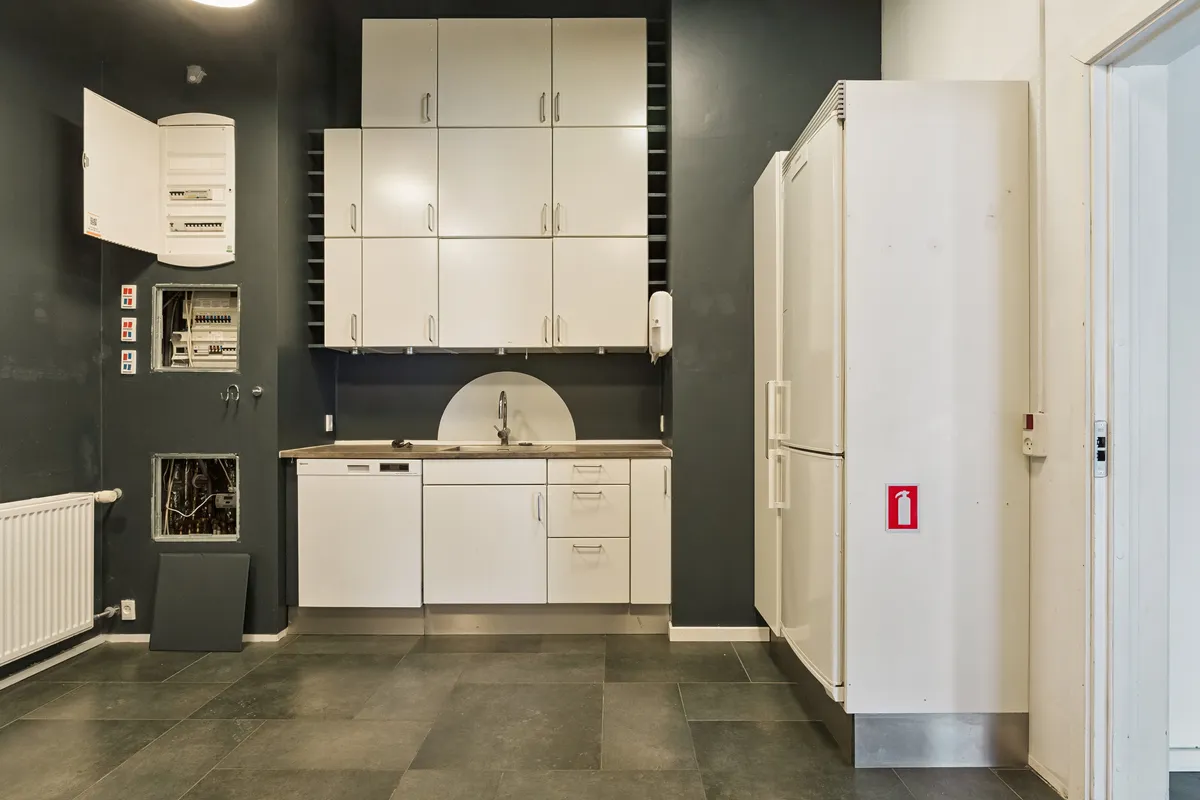 Butik til leje på Amerika Plads 34, st., 2100 København Ø. Nyd det indbydende køkken med hvide skabe og en hvid køleskab ved siden af