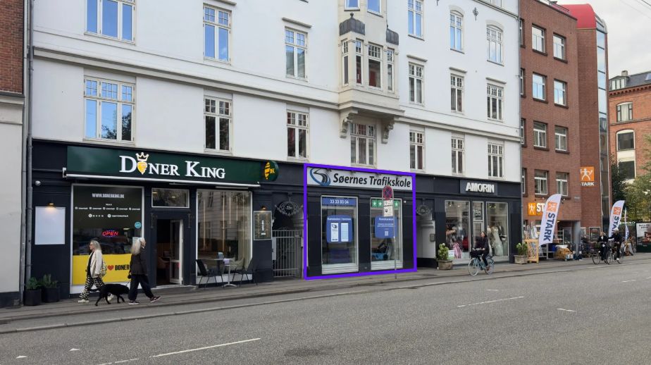 Strækningen Falkoner Allé med forretninger som Døner King og Söernes Træfikskole og folk som går og cykler langs gaden med smukke bygninger på hver side