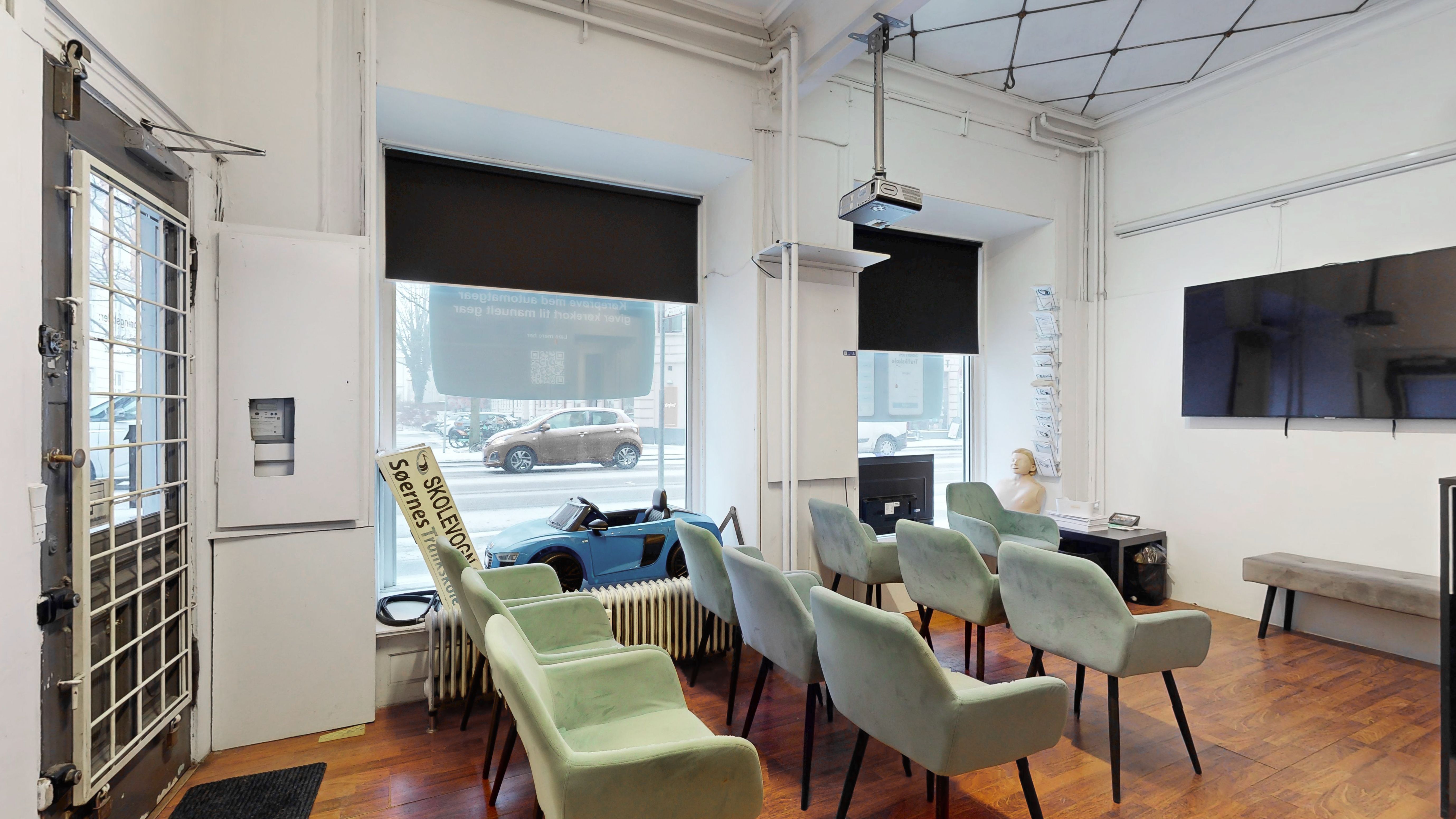 Erhvervslejemål med synlig placering i stueetagen, møbler, tv, projektor og to bilmodeller i vinduet