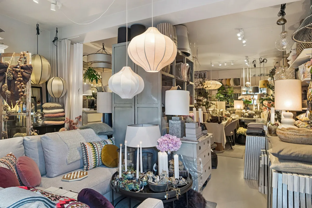 Interiør med sofaer og stole, hvide og grå farver, små hvide lysekroner, lyse og puder, gulve og vægge, hyggeligt og klassisk design, indretning, møbler og tekstiler, hjem.