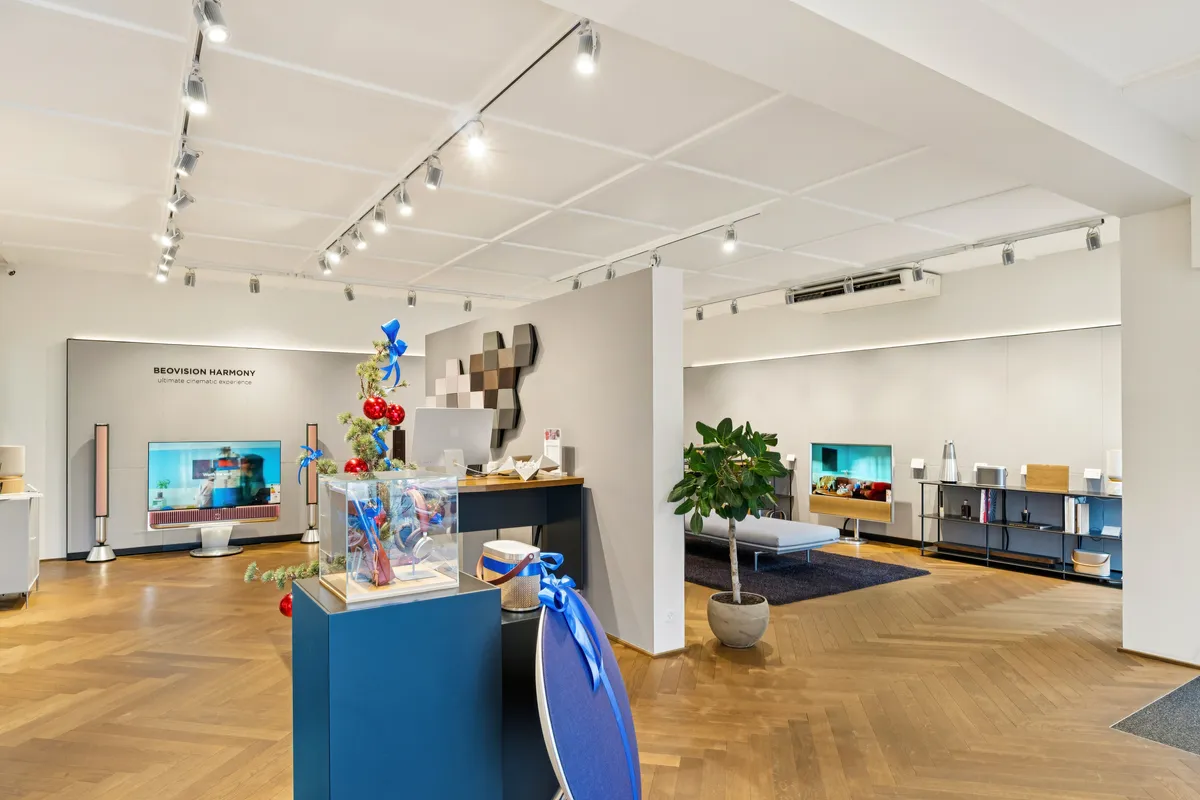 Luksuriøs indretning med tv-skærme, højtalere, skrivebord og senge. Et eksklusivt værelse med masser af møbler og tekstiler. Elegant indretning med lyse gulve og hvide vægge