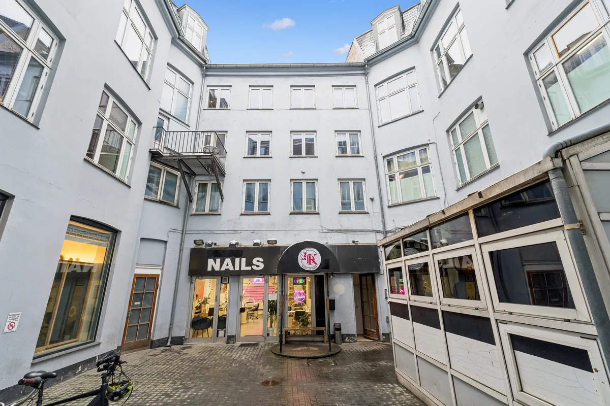 En cykel parkeret ved en kontordør med navnet Nails på facaden og et skilt med adgangstid og lukket i øjeblikket.