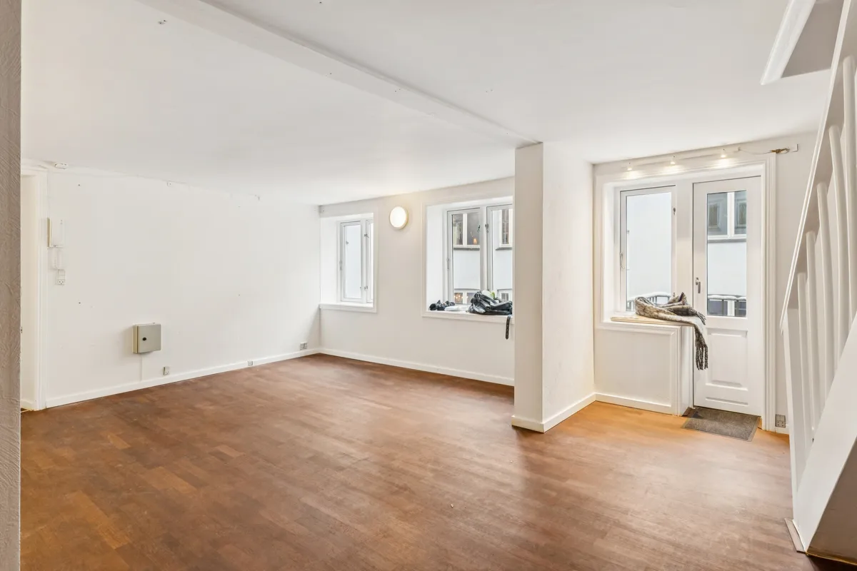 Kontor med lys og lyse gulve, åbne ruder og et vindue med et sølvfarvet ruderamme. Der er en hvid dør og en trappe med hvide sider.