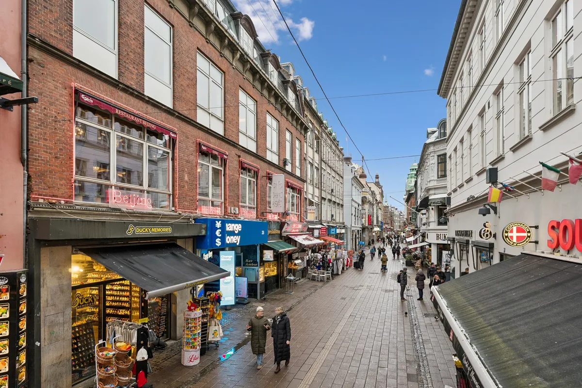 Dansk kontor på Frederiksberggade med mange butikker og mennesker, der går forbi og går ind i de forskelige butikker.
