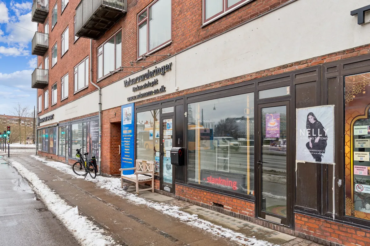 Butik til leje med adressen Åboulevard 1, st. 3, 1635 København V. Butikken er i et rødt murstenshus med en slanknindgangsskilt og en lille butiksbank.