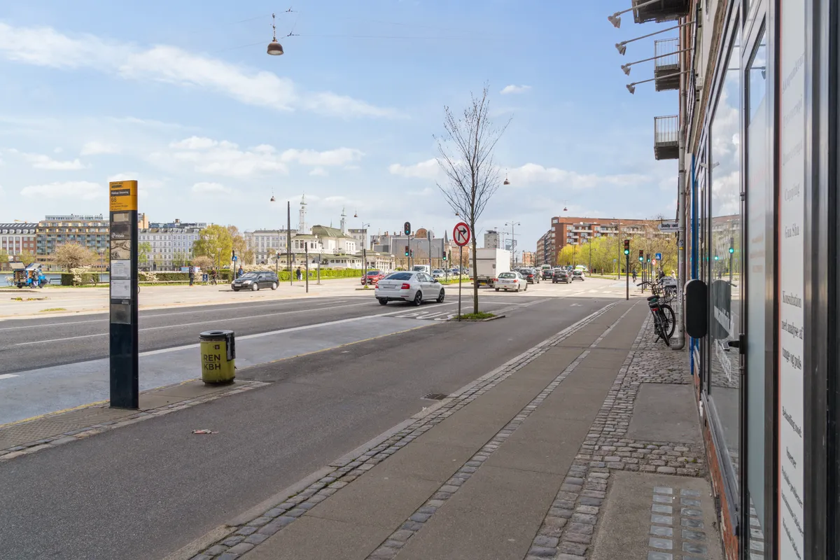Butik på Åboulevard med udsigt over gaden og biler, der kører forbi, samt en bygning med facade og vinduer