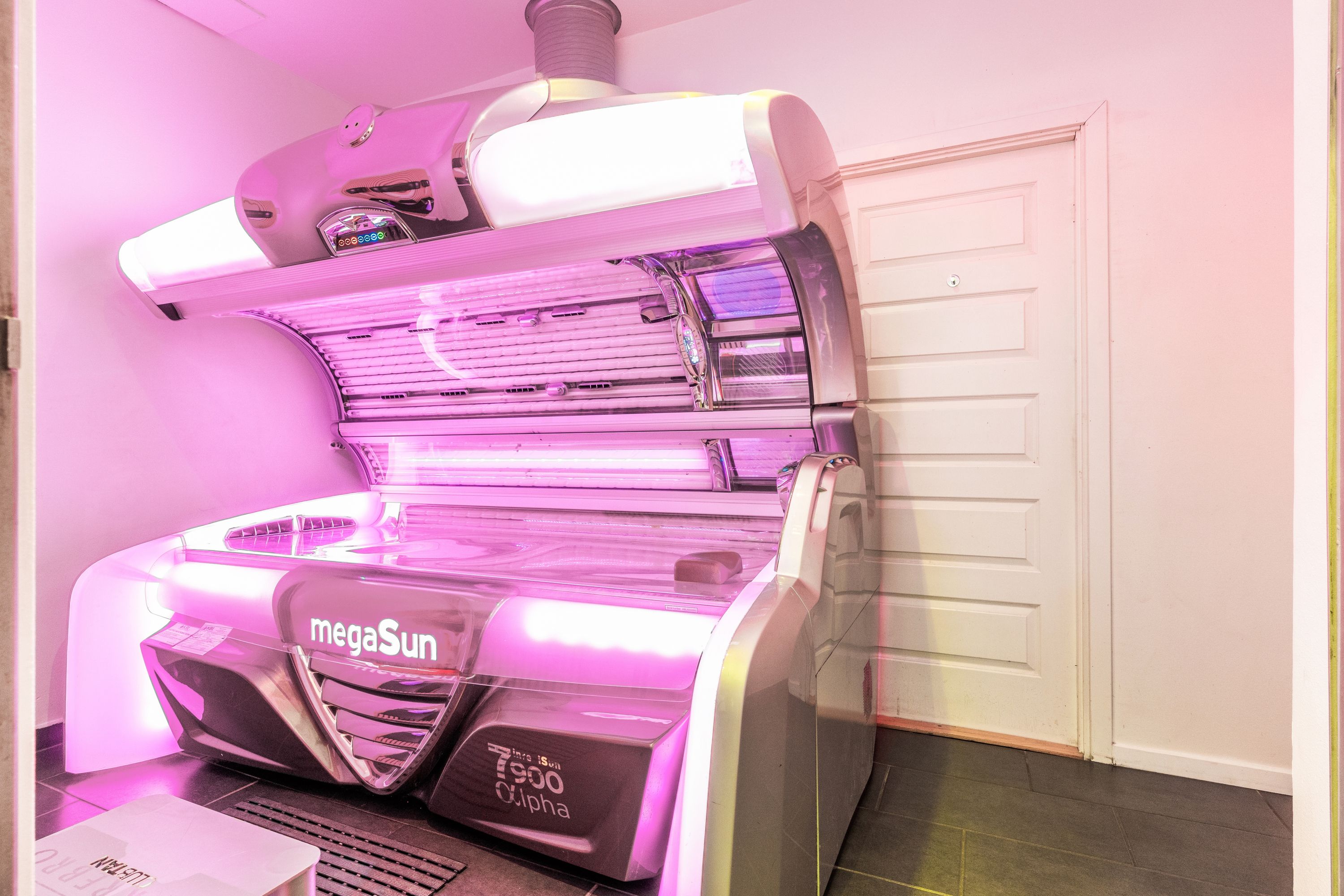 Solcenter med MegaSun solseng i pink lys i en hvid, rummelig butik med lysegult loft og gulv