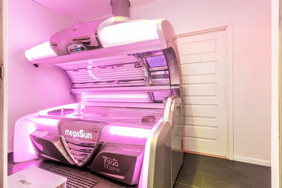Solcenter med MegaSun solseng i pink lys i en hvid, rummelig butik med lysegult loft og gulv