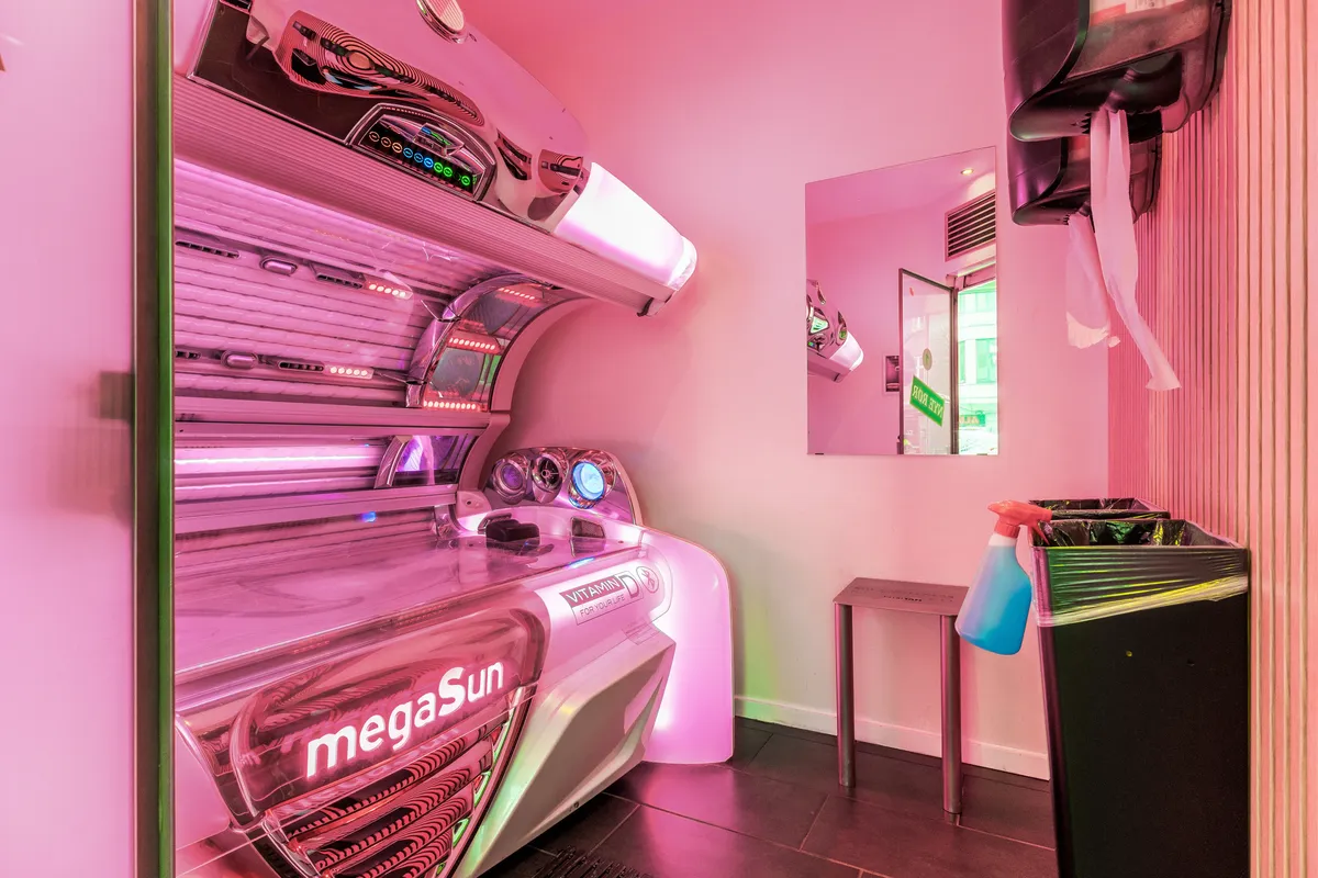 Solseng i pink farve, en pink skraber, en dispenser og en afløbssøjle i en pink og hvid butik med et spejl og en bord