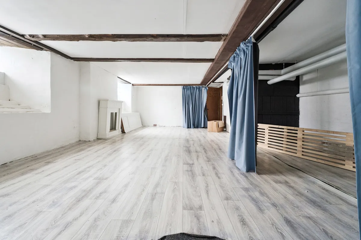 Store, lyse lokaler med hvidt loft og gulv samt blå gardiner i fuld højde i en stor bygning