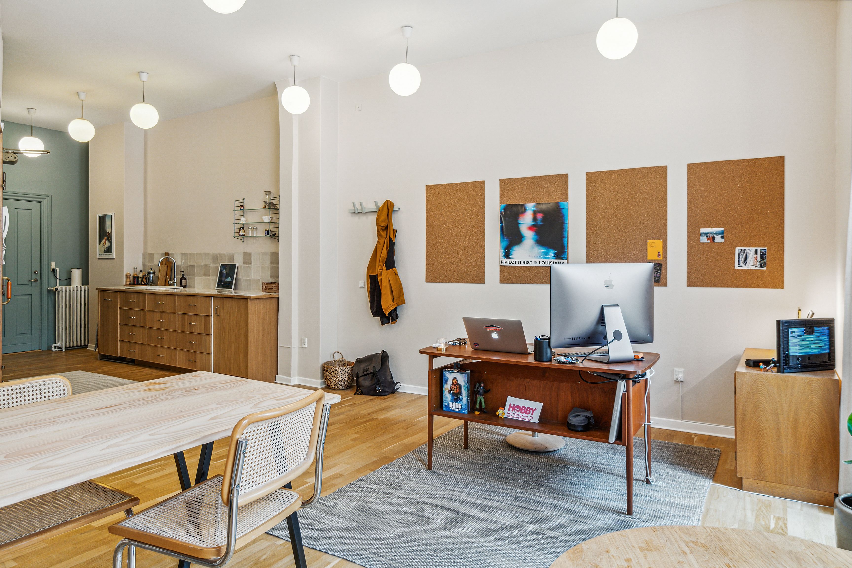 Kontor til leje med computere, stole, bord, sofa, trægulv, korkspalter og lysekroner på loftet