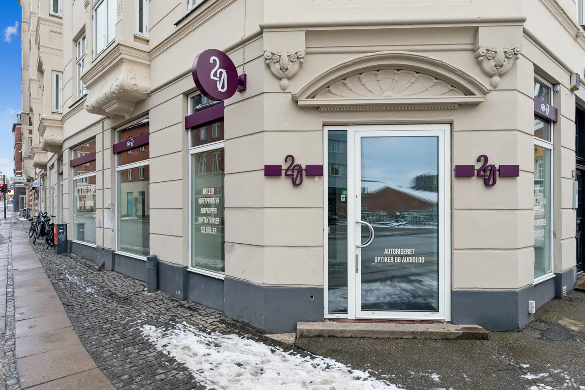 Valby Langgade 49B butik med teksten "Autorisert Optiker og Audiolog" og store glasruder, snødækket fortov og gadebelysning